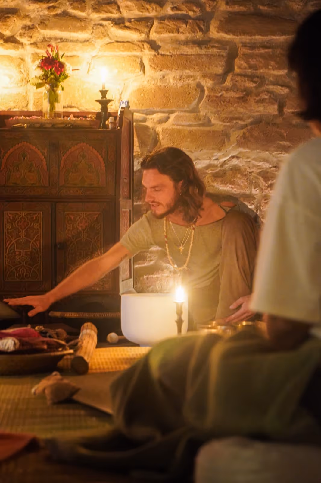 Morgan playing singing bowls in an intimate candlelit session lit in warm purple tones